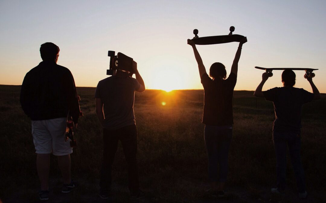 group of people holding skateboards under sunset