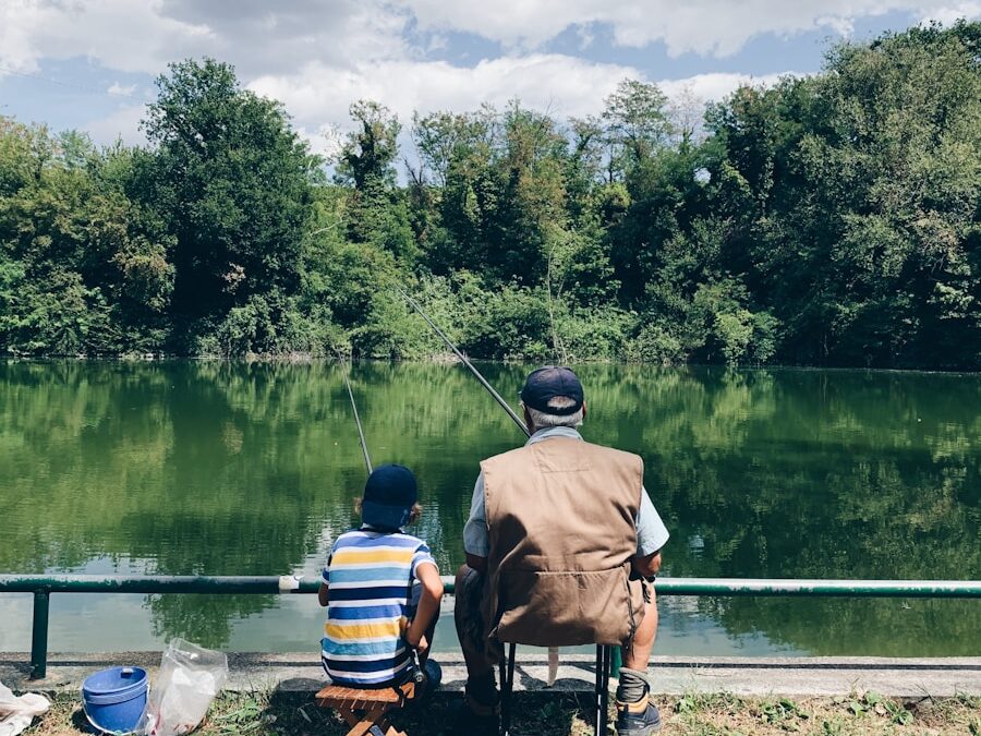 man in black shirt sitting on chair near lake during daytime